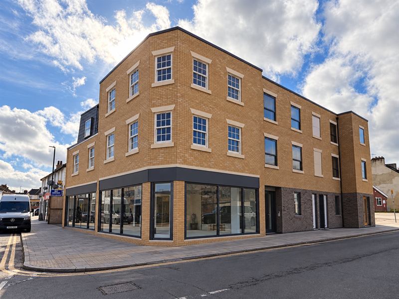 Three-storey brick mixed-use building with shopfronts on a street corner