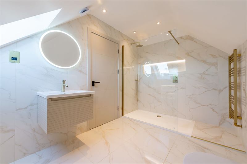 Marble-tiled shower room with illuminated mirror